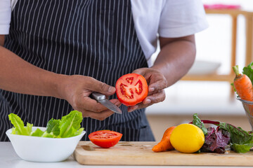 Senior men washes fresh corn by water in the kitchen for good health .There are fresh eggs on the table for preparing food.Senior life
