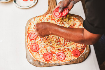 Latino man preparing artisanal pizza. Making pizza in a wood oven, vegan pizza, pizza amazon....