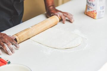 Latino man preparing artisanal pizza. Making pizza in a wood oven, vegan pizza, pizza amazon. Cheese and tomato on pizza. Fast food preparation. Tomato sauce, cheese and tomato.