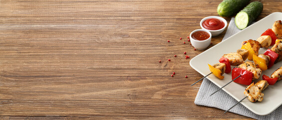 Plate with grilled chicken skewers and vegetables on wooden background with space for text