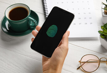 Woman with smartphone using fingerprint scanner to login into personal account at workplace