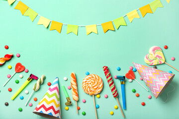 Composition with sweet lollipops and birthday hats on color background