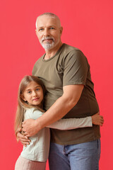 Little girl with her grandfather hugging on red background