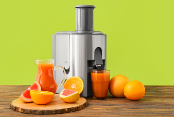 New modern juicer and glass of fresh juice with fruits on wooden table