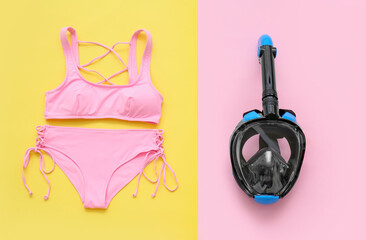 Female swimsuit with snorkeling mask on color background