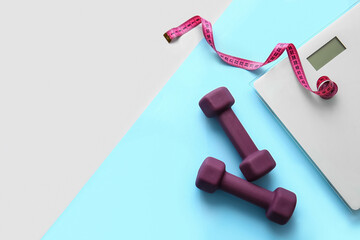 Dumbbells, measuring tape and scales on color background