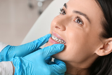 Beautiful woman with dental braces visiting dentist in clinic, closeup - obrazy, fototapety, plakaty