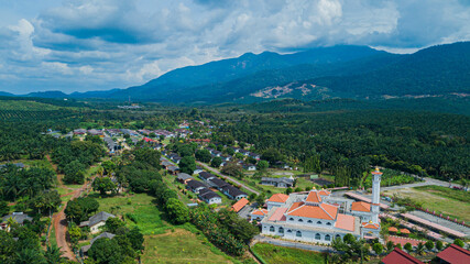 Fototapeta premium Aerial drone view of Tun Khalil Mosque with mountain background at Asahan, Melaka, Malaysia.