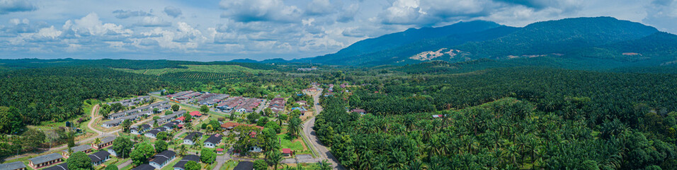 Fototapeta na wymiar Panoramic aerial drone view of oil palm plantations land and workers settlements in Asahan, Melaka, Malaysia.