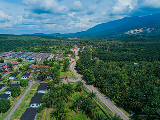 Aerial drone view of oil palm plantations land and workers settlements in Asahan, Melaka, Malaysia.