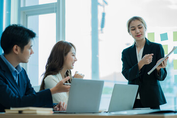 A group of young Asian businessmen working as a team brainstorm, analyze a financial chart, or discuss a marketing plan. Women leaders present and plan new business strategies. teamwork concept