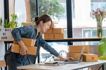 Young businesswoman in Asia packs products in cardboard boxes and sends customers work from home...