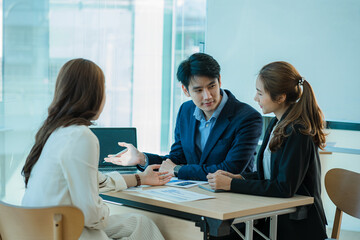 A group of young Asian businessmen working as a team brainstorm, analyze a financial chart, or discuss a marketing plan. Women leaders present and plan new business strategies. teamwork concept