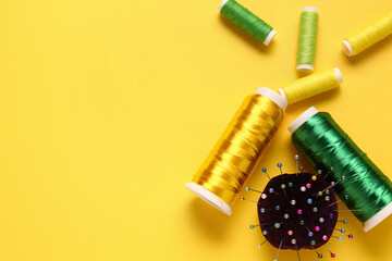 Thread spools and ball pins on yellow background