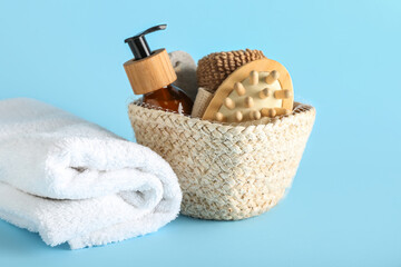 Basket with bath supplies and clean towel on color background
