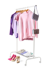 Rack with female clothes, shoes and bags on white background