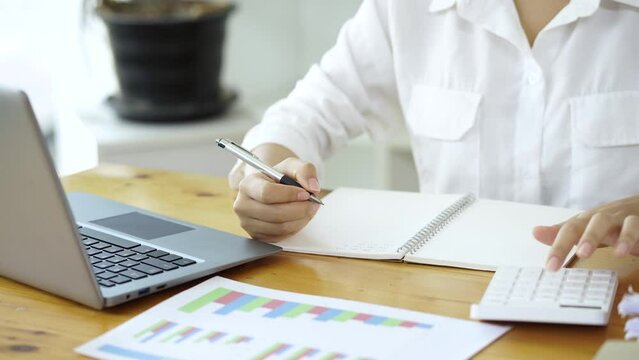 Close up of Businesswoman accountant using a calculator calculating expenses, analysis financial data, and taking notes on notebook.