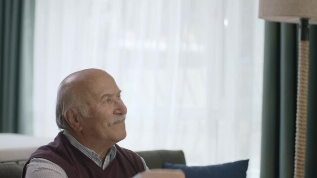 A woman in hijab visits her father during Eid Mubarak (Turkish Ramadan or Şeker Bayram). The woman kisses her father's hand to show respect. Muslim holiday traditions concept.