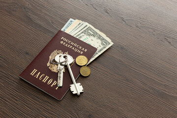 On the table there is a Russian passport inside various dollar bills and small change. House keys