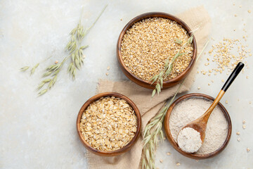 Dry oatmeal in bowl on light background.