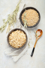 Dry oatmeal in bowl on light background.