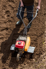Banner. A male farmer plows the land with a cultivator. Agricultural machinery for tillage in the...