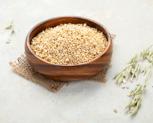 Dry oatmeal in bowl on light background.