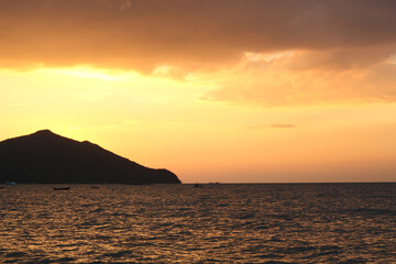 The dark orange sky is beautiful in the evening with the mountains and the sea at sunset.