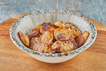 Stir-fried potatoes in a plate on wooden board