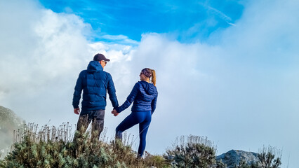 Couple with scenic view from Monte Comune on thick white clouds and blue sky near coastal town...