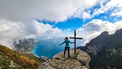 Active woman at summit cross near Santa Maria del Castello. Scenic view on coastal town Positano,...