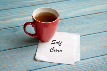 Self care, text on napkin, next to a cup of coffee on table. Self care or love yourself concept.