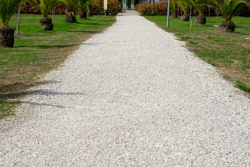 White gravel road in the park. White road stretching into the distance.