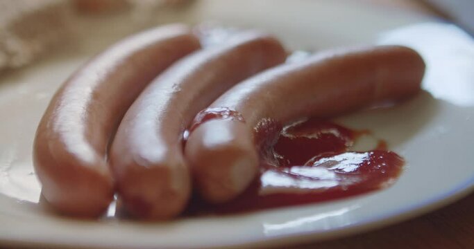 Dipping a sausage in ketchup. Close-up shot