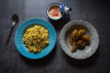 Indian meal pulao made of basmati rice and chicken curry served in bowl on a dark background. Top view, selective focus.