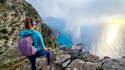 Woman with scenic view from a hiking trail on the coastal driving road of beautiful Amalfi Coast,...
