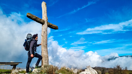 Active man with backpack at summit cross of Monte Comune, Lattari Mountains, Apennines, Amalfi...