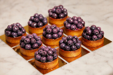 Closeup group of delicious tarts with berries served on golden paper. Restaurant sweet bakery.