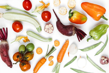 Food concept. Pattern made of autumn vegetables. Tomatoes, onion, cucumber, carrot, garlic, red beet, pepper, zucchini, maize and green haricot on white studio background wall. Flat lay, top view