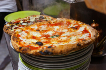 Pizza margherita napoletana fumante e appena sfornata con sugo di pomodoro, mozzarella di bufala e basilico fresco 