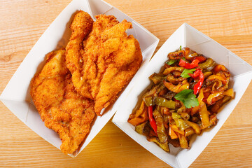 Vaschette di cartone per alimenti con cotoletta di pollo e peperoni preparate per un pranzo da...
