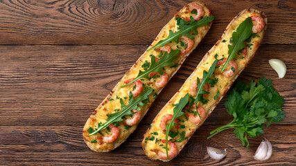 Homemade baguette sandwich or pizza with shrimp, garlic fresh rocket salad and parsley. Top view photo on a wooden background with place for your text.
