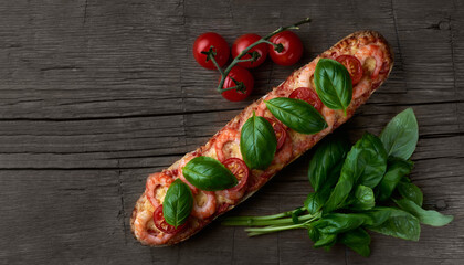 Homemade baguette sandwich or pizza with shrimp, cherry tomatoes and fresh basil leaves on top. Top view photo on a wooden background in a rustic style with place for your text.
