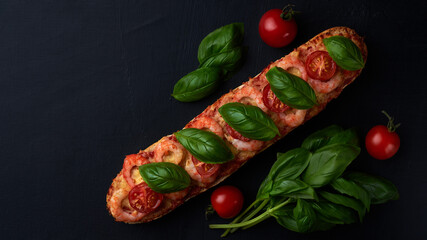Homemade baguette sandwich or pizza with shrimp, cherry tomatoes and fresh basil leaves on top. Top view photo on a dark background with place for your text.