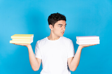Hispanic teenager boy holding books on hands and looking with disgusted face to subject