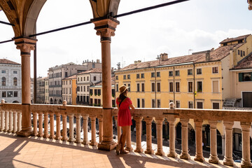 Tourist woman in red dress with scenic view on Piazza delle Erbe from loggia, external balcony of...