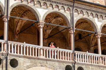 Tourist woman in red dress with scenic view on Piazza delle Erbe from loggia, external balcony of...