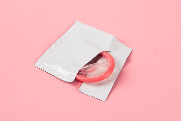 opened condom in pack on pink background. 