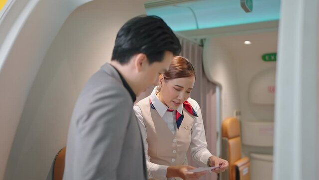 Passengers boarding the plane with boarding pass checked by flight attendants or cabin crew while welcoming them at plane entrance. 