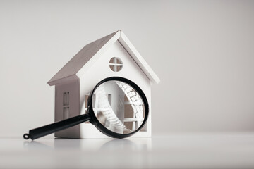 Magnifying glass and white house model. House selection and search, real estate concept